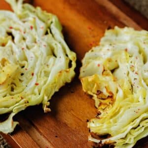 roasted cabbage with red pepper flakes on cutting board with butter knife