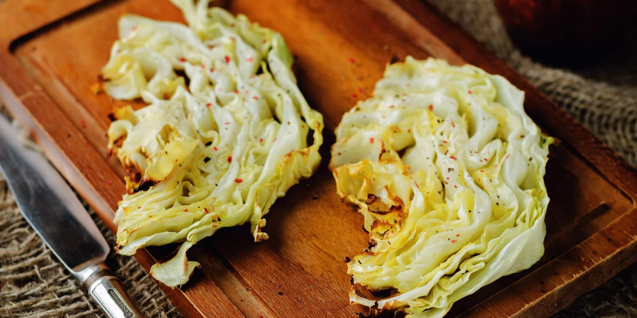 roasted cabbage with red pepper flakes on cutting board with butter knife